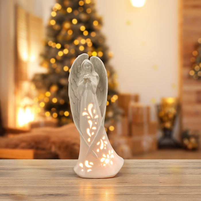 Porcelain light up angel on table with christmas tree in the background